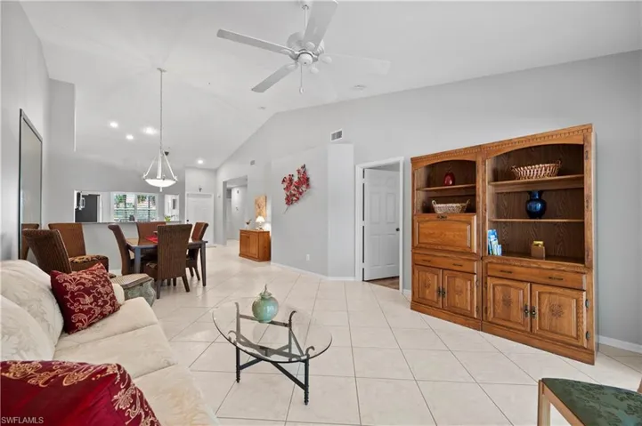 Living room with ceiling fan, light tile patterned floors, and high vaulted ceiling