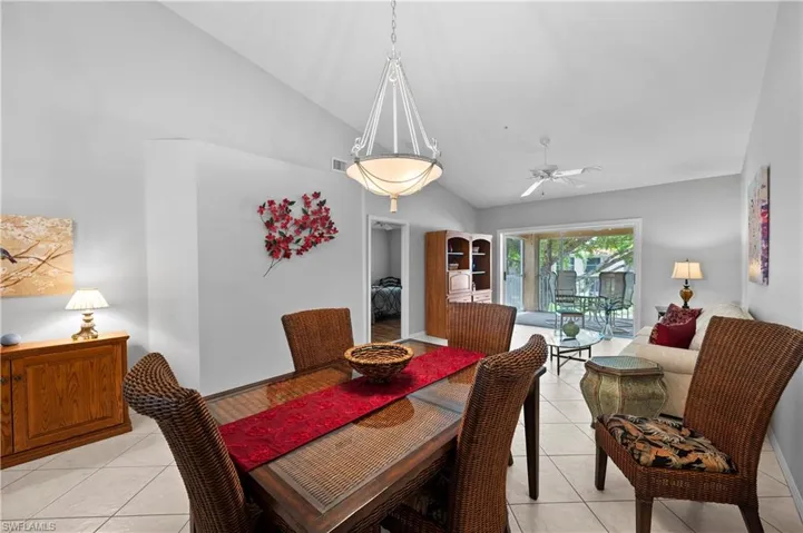 Dining room with light tile patterned floors, high vaulted ceiling, and a ceiling fan