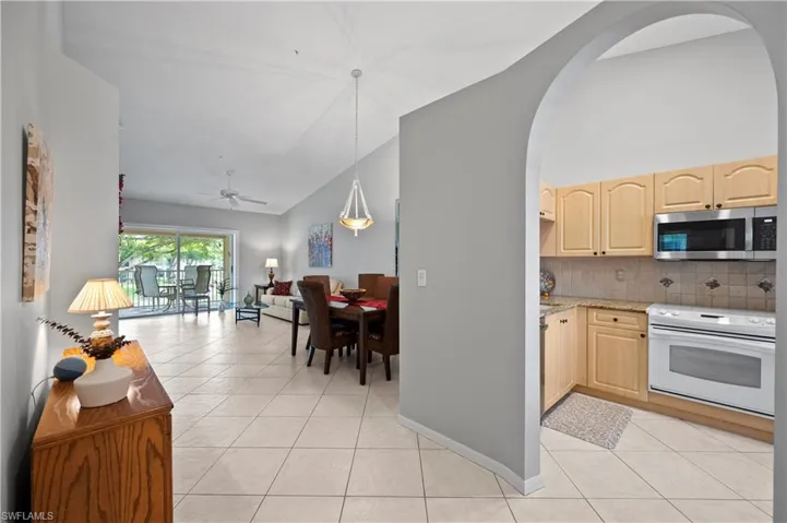 Kitchen featuring stainless steel microwave, white range with electric stovetop, light brown cabinets, light tile patterned flooring, and open floor plan