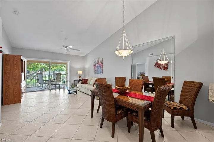 Dining space with high vaulted ceiling, ceiling fan, and light tile patterned flooring
