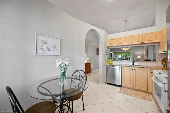 Kitchen with stainless steel dishwasher, electric range, light brown cabinetry, and arched walkways