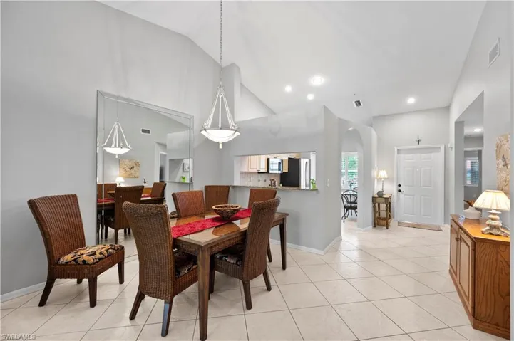 Dining room featuring high vaulted ceiling, light tile patterned flooring, and recessed lighting