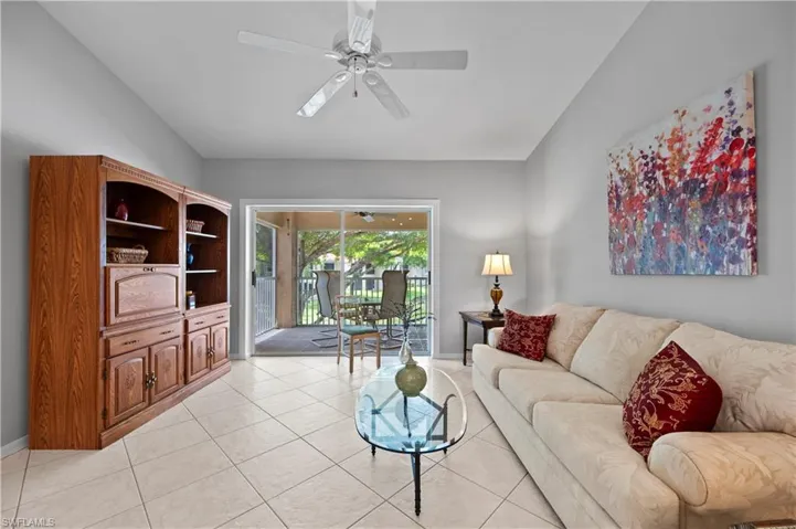 Living room featuring lofted ceiling, ceiling fan, and light tile patterned floors