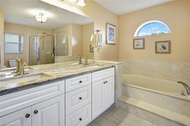 Primary bathroom with porcelian tile floors, double vanity, garden soaking tub, toilet, and walk in shower and linnen closet