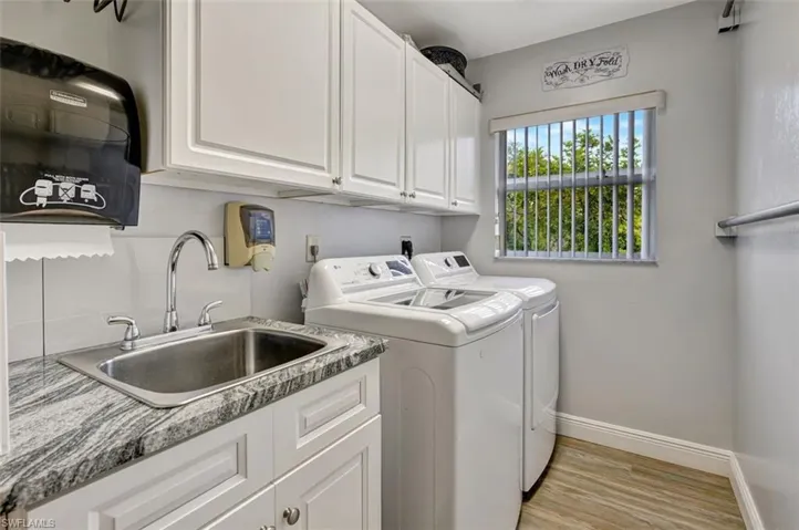 Laundry area featuring cabinets, independent washer and dryer, light wood-type flooring, sink, and hookup for an electric dryer
