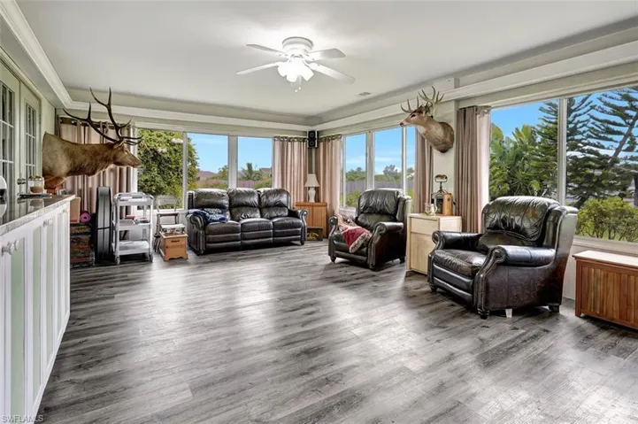 Sun room featuring wood-type flooring, ceiling fan, and crown molding