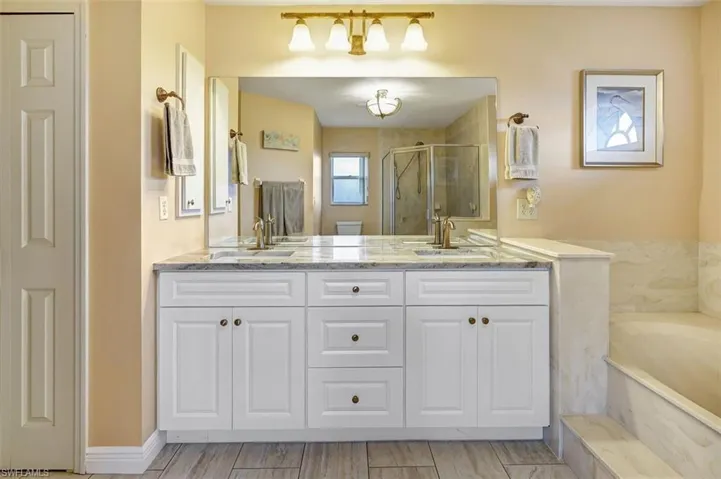Primary Bathroom with porcelian tile flooring, garden soaking tub, plus walk in shower, and double sink vanity with granite tops and linnen closet