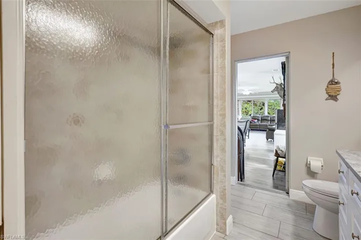 Guest bathroom featuring shower/bath combination with glass door, and door to sunroom
