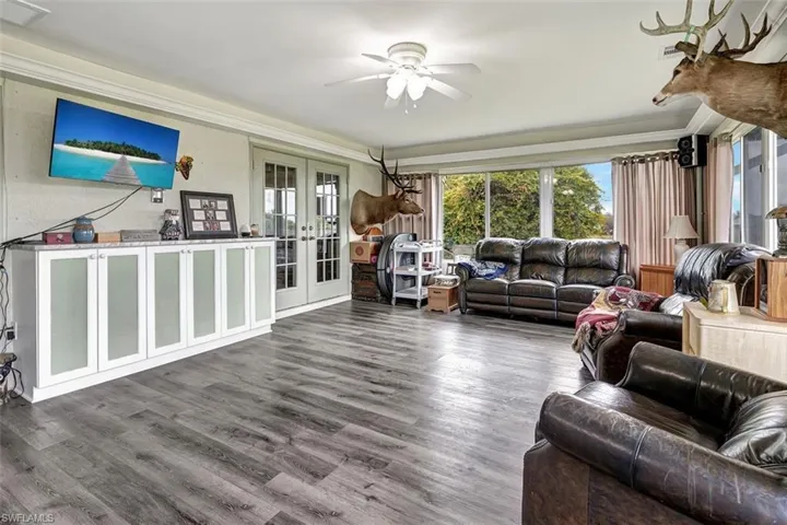 Sun room featuring built in cabinets with granite tops, wood-type flooring, ceiling fan, french doors, and crown molding