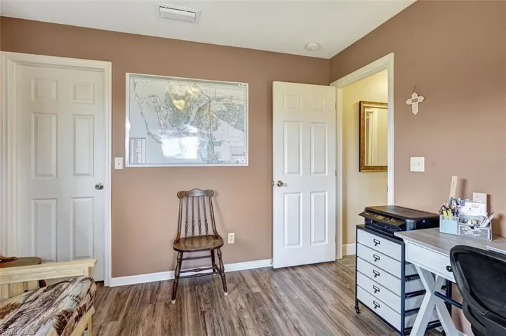 Bedroom/Home office featuring spacious walk-in closet and hardwood / wood-style flooring