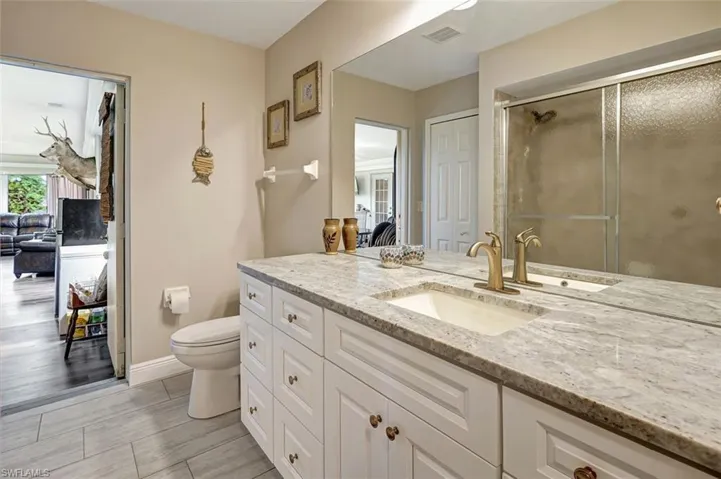 Guest bathroom with vanity with extensive cabinet space, linnen closet, glass enclosed tub/shower, porcelian tile flooring