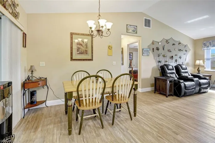 Dining room featuring a notable chandelier, vaulted ceiling, and light wood-type flooring