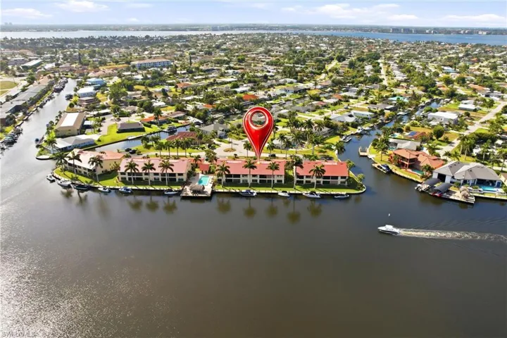 Waterfront condominium community featuring a communal swimming pool, private boat docks, and mature palm trees