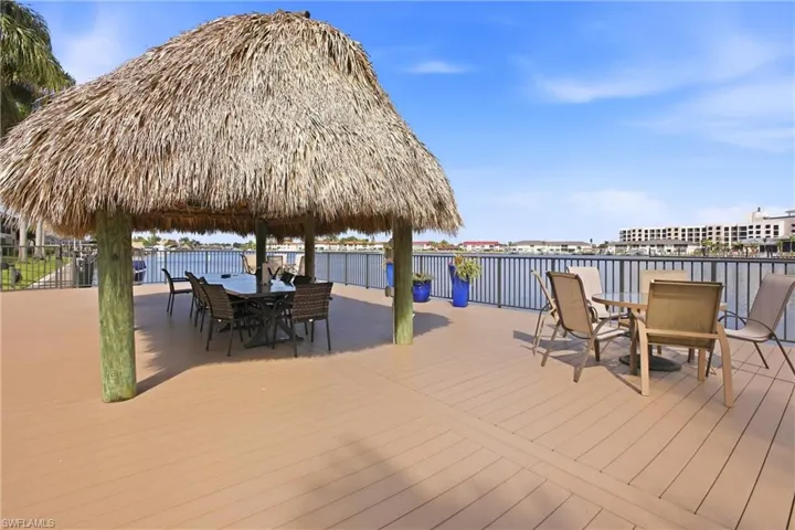Expansive waterfront deck featuring a substantial tiki-style thatched roof structure