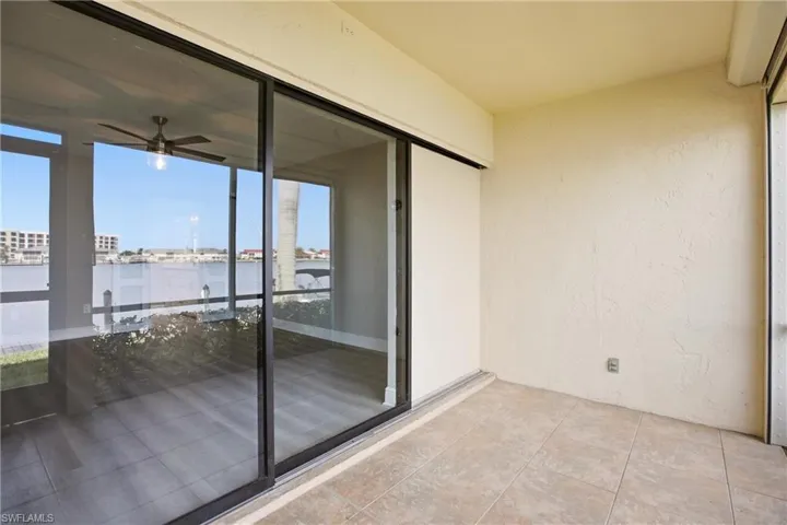 Covered patio featuring ceramic tile flooring and direct access to an enclosed sunroom with water frontage