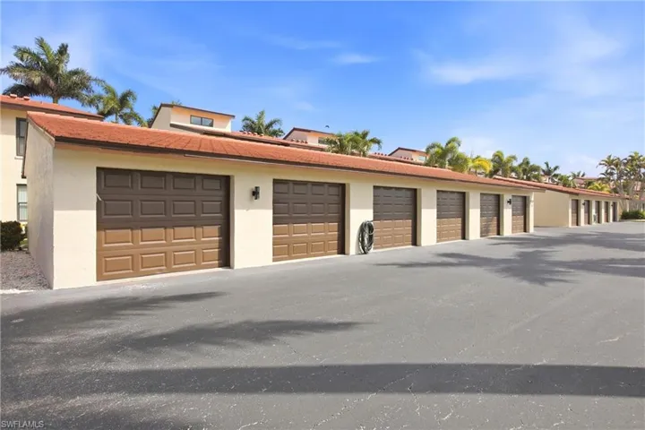 Row of attached garages featuring two-tone brown paneled doors and exterior wall sconces