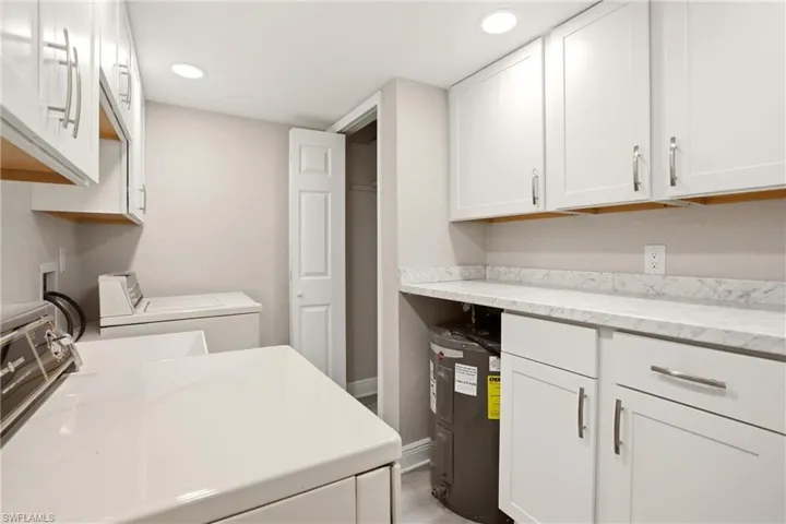 Laundry area featuring white cabinetry with brushed nickel hardware, light-toned countertops, and recessed lighting