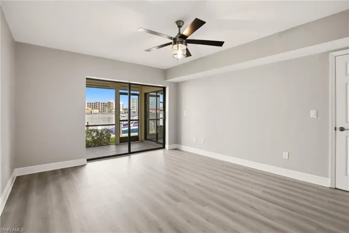 Spacious interior featuring wood-finish flooring, a contemporary ceiling fan, and sliding glass doors leading to a private screened balcony