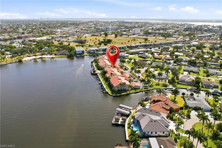 Waterfront community featuring canal access, mature palm trees, and established residences with tile roofs