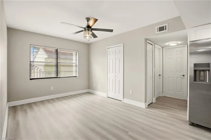 Open concept living area featuring light wood-finish flooring, a contemporary ceiling fan with integrated lighting, and neutral wall tones