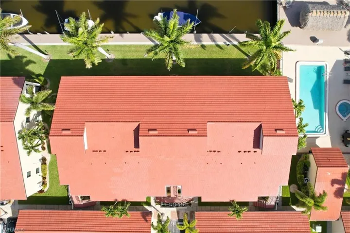 Terracotta tile roofing atop a multi-unit complex, featuring a private swimming pool, spa, and waterfront access with boat slips