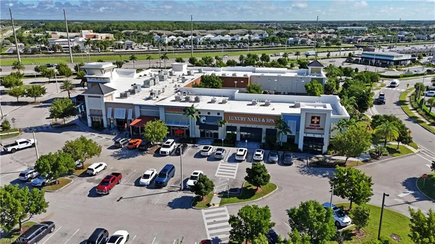 Multi-tenant commercial building with varied exterior finishes, surface parking, and mature landscaping