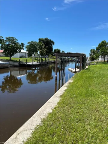 View of dock with a water view and a lawn
