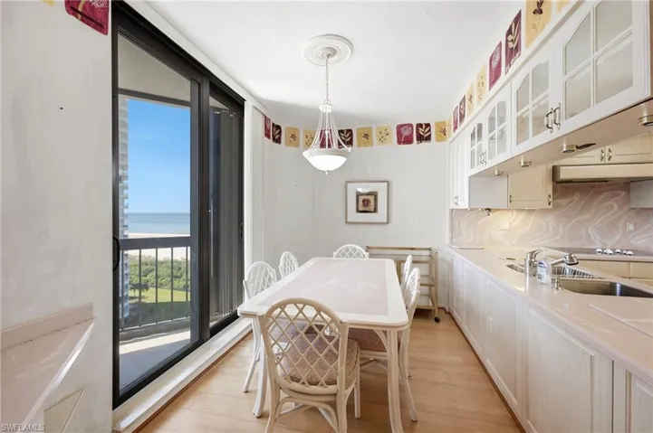 Sliding glass doors, wood-finish flooring, white cabinetry with glass inserts, integrated sink, and a light fixture with a decorative ceiling medallion