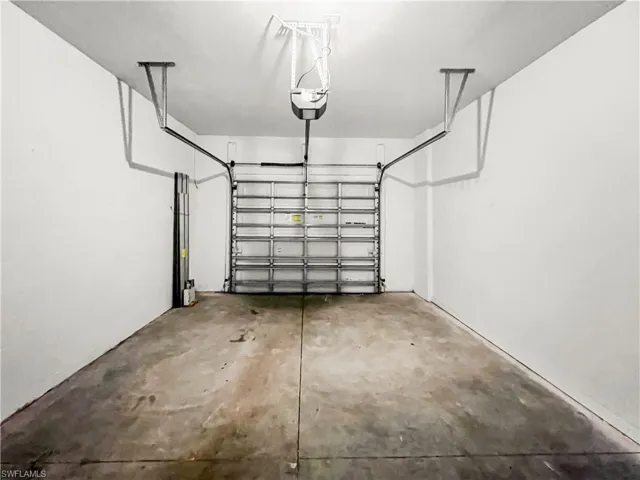 Attached garage featuring a sectional door, automatic opener, and concrete flooring