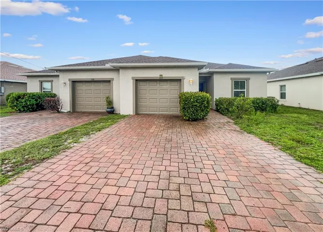 Exterior featuring a stucco finish, two single-car garages, and a paver driveway