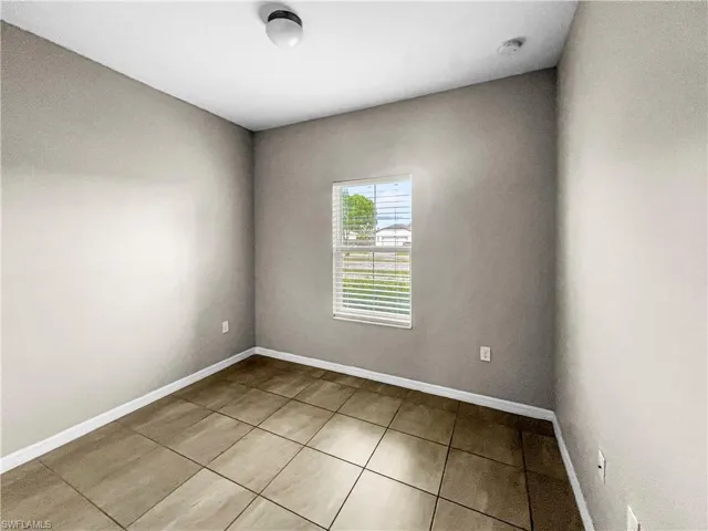 Neutral-toned interior with tile flooring and a window featuring horizontal blinds