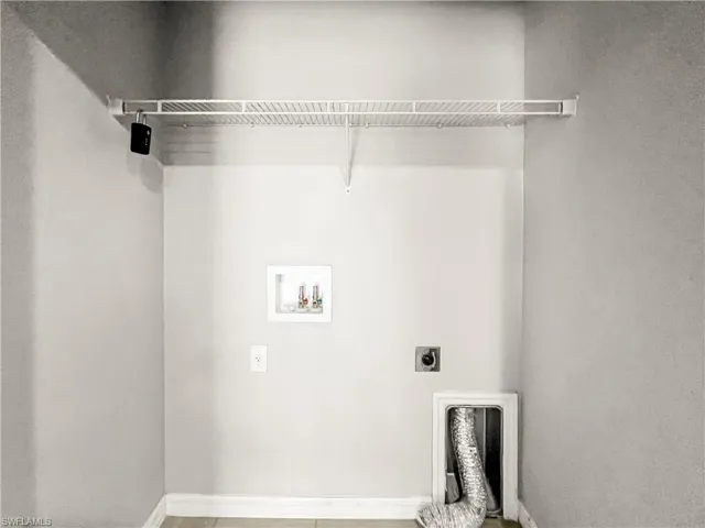 Dedicated laundry area featuring a white wire shelving unit, washer hookups, dryer vent, and electrical outlet