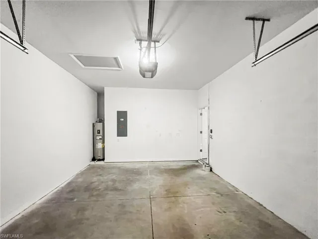 Spacious garage featuring a concrete floor, overhead lighting, and an access door