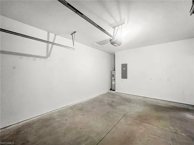 Spacious garage featuring a concrete floor, painted white walls, overhead garage door rails, and a garage door opener system