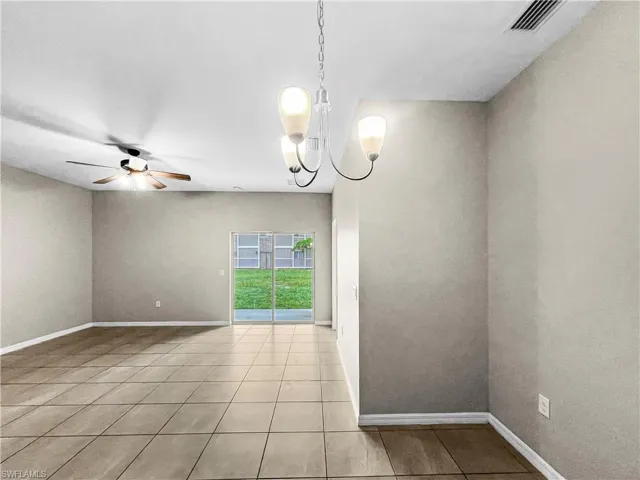 Spacious interior featuring neutral wall tones, tile flooring, a ceiling fan, and a contemporary chandelier