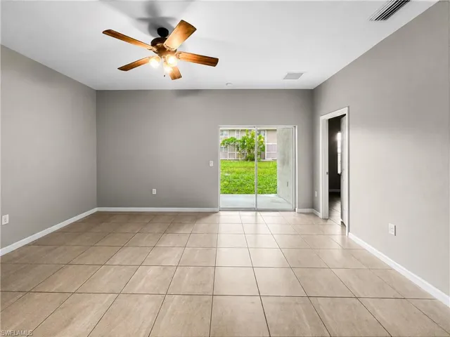 Spacious interior room featuring neutral wall tones and a wood-finish ceiling fan