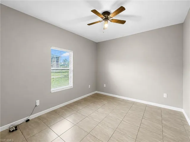 Neutral-toned room featuring a single window with blinds, tile flooring, and a ceiling fan with light fixture