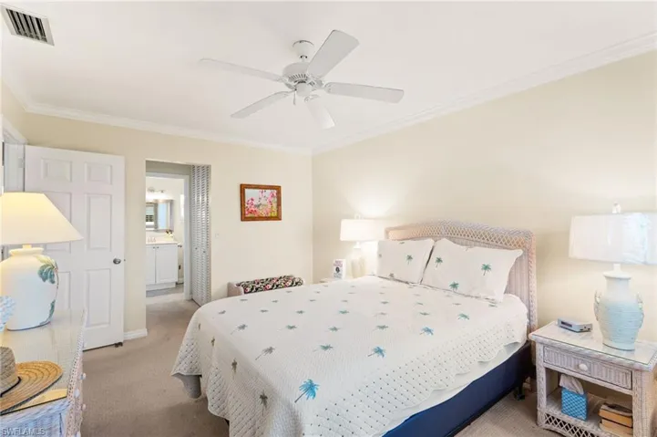 Primary Bedroom featuring ceiling fan, connected bathroom, light colored carpet, and ornamental molding