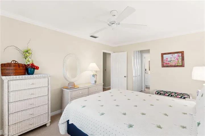 Carpeted Primary bedroom with ceiling fan, ornamental molding, and baseboards