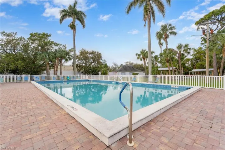 Heated Community pool featuring fence and a patio