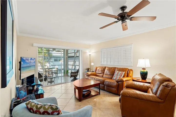 Living area with ceiling fan, light tile patterned flooring, and crown molding