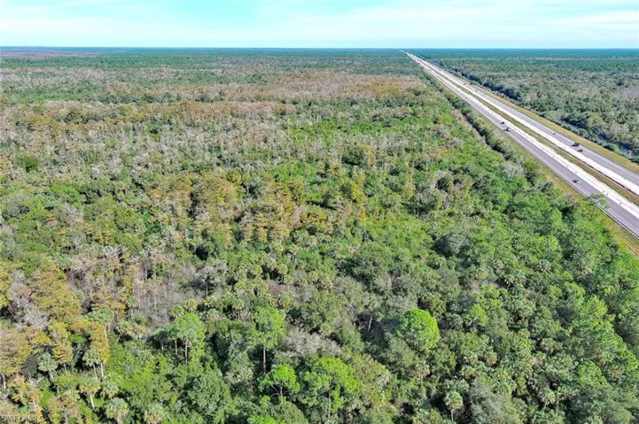 Aerial view of property's location with a major roadway and a forest