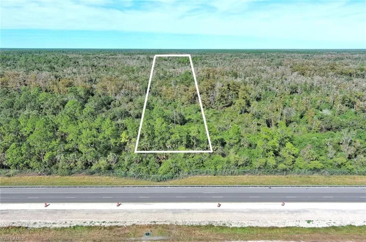 Aerial view of property's location featuring property parcel outlined and a heavily wooded area