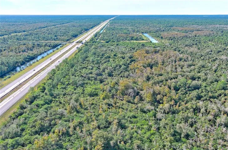 Aerial overview of property's location with a forest and a large body of water