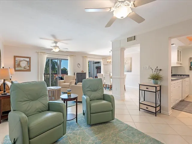 Living area featuring light tile patterned floors, ornamental molding, a ceiling fan, and a chandelier
