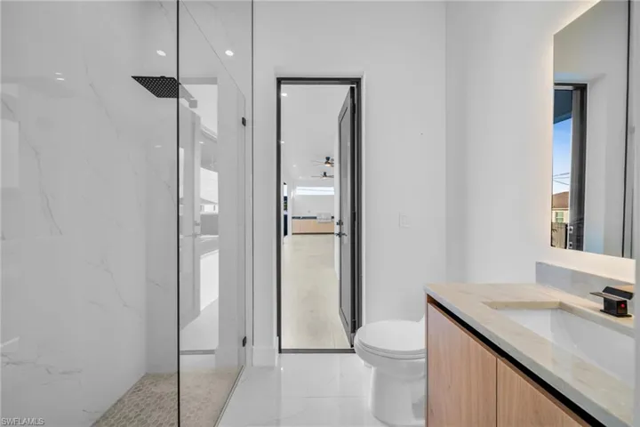 Bathroom with vanity, a marble finish shower, light marble finish floors, and recessed lighting
