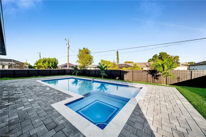 View of pool with a patio area, a fenced backyard, and a pool with connected hot tub