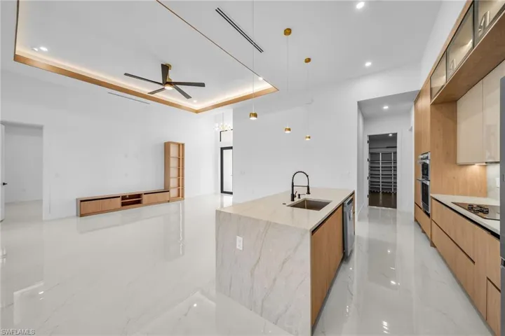 Kitchen featuring light marble finish flooring, open floor plan, modern cabinets, ceiling fan, and hanging light fixtures