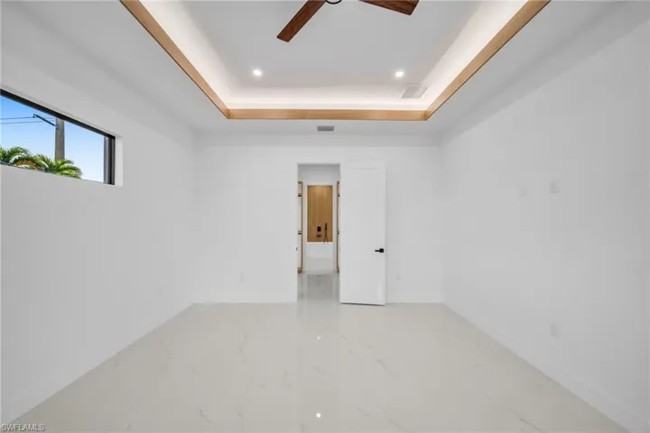 Spare room with a raised ceiling, recessed lighting, ceiling fan, and light marble finish floors