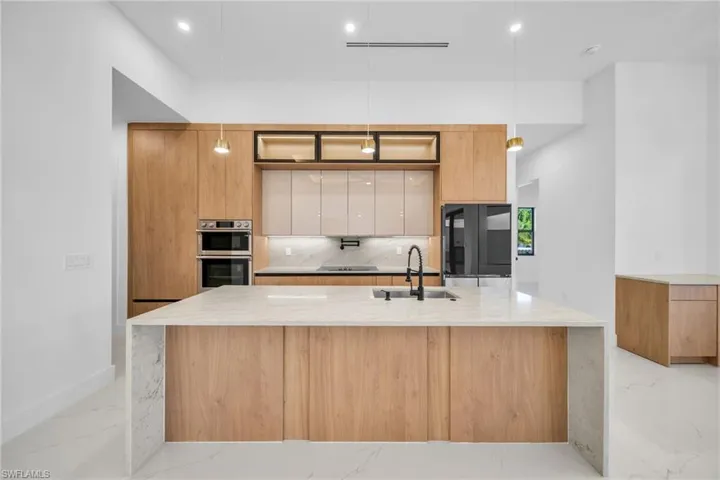 Kitchen featuring modern cabinets, light stone countertops, pendant lighting, and recessed lighting